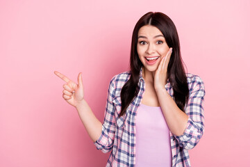 Portrait of attractive amazed cheerful girl demonstrating copy empty space ad isolated over pink pastel color background
