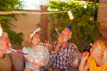 Senior friends blowing party whistles at a birthday party