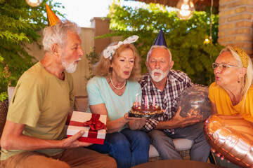 Elderly people blowing candles on a birthday cake