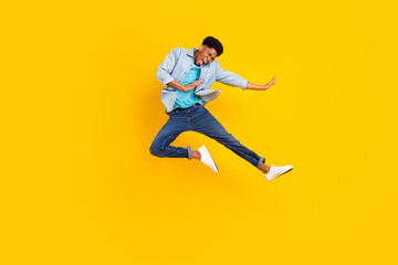 Fototapeta na wymiar Photo of cool funny dark skin guy dressed denim shirt practicing karate jumping high isolated yellow color background