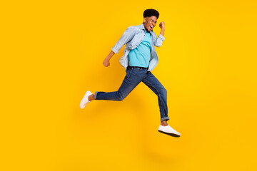Fototapeta na wymiar Photo of funky charming dark skin man wear jeans shirt jumping high running fast isolated yellow color background