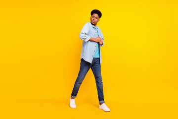 Photo of cool handsome dark skin guy dressed denim shirt walking dancing isolated yellow color background