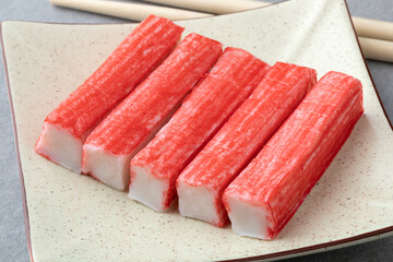 Plate with red Japanese Surimi sticks close up   