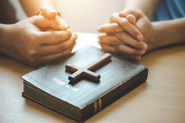 Hands of Christian group Pray for god blessing with the bible on a wooden table. begging for...
