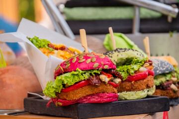 Close up: fresh colorful vegan burgers with vegetables on counter at summer local food market. Outdoor cooking, gastronomy, vegetarian, street food concept
