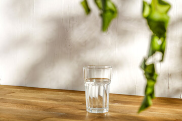 Glass of water and table with wall and shadows 