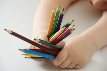 Naklejka premium hands with pencils. The child is holding a lot of colorful pencils for drawing.