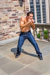 Dressing in jeans and leather sneakers and shirtless, a handsome, muscular guy is waving arms and...