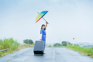 スーツケースとカラフルな傘を持つ女性