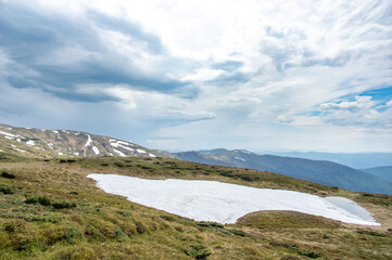 Spring mountains in the snow on the background of a green forest