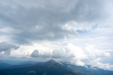 Mount Hoverla in early summer in snow and green grass against a background of blue sky