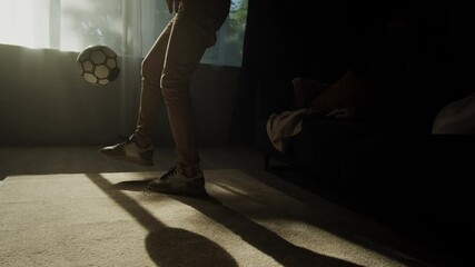 Man professional football player training and controlling a soccer ball in the living room at home or office, coronavirus covid 19 lockdown. - Powered by Adobe