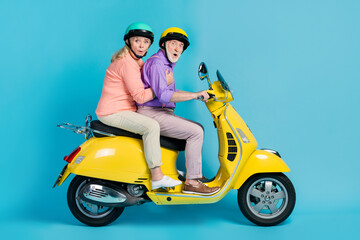 Fototapeta na wymiar Portrait of two amazed elderly retired pensioners riding moped pout lips weekend isolated over bright blue color background