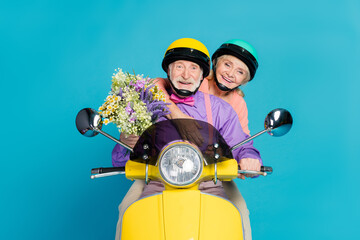Fototapeta na wymiar Photo of grey haired retired pensioner husband wife couple ride bike hold flowers isolated on blue color background