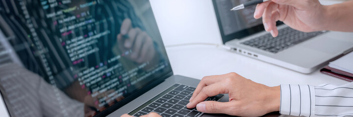 programmer writing program code with two monitors and working on a new software or hacker...