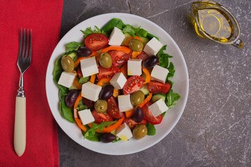 Top view on a plate of Greek salad on dark table. Mediterranean cuisine. Healthy food.