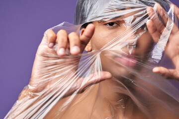 Close up horizontal portrait of young man tear up plastic bag with look eyes. Freedom of transgender