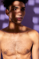 Close-up verticale portrait of young man posing with shadow on face. Model transgender. Naked torso