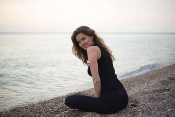 Fototapeta na wymiar young beautiful woman meditates while sitting by the sea