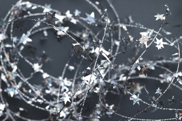 Beautiful Christmas background from silver twisted wire with stars on a blurred gray. Magical New Year mood. Decoration for home or Christmas tree. Selective soft focus