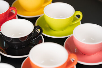 Obraz na płótnie Canvas Side view cup of coffee colorful alternating colors is bright Red, Yellow, Orange, Green, Gray, Black and saucer for background in coffee shop.