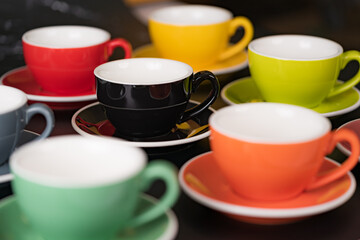 Side view cup of coffee colorful alternating colors is bright Red, Yellow, Orange, Green, Gray, Black and saucer for background in coffee shop.