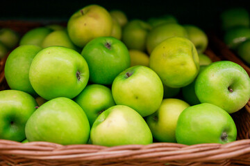 Naklejka na ściany i meble juicy green apples lie in a basket on the counter of the store