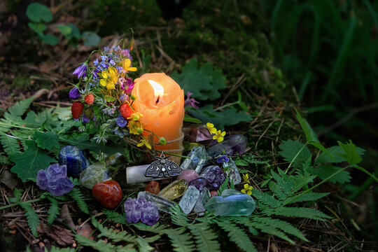candle, mineral gemstones, flowers on dark forest natural background. Magic, Witchcraft, spiritual practice. pagan, Wiccan, Slavic traditions. esoteric ritual for Midsummer, Litha