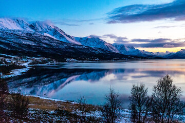 frisch verschneite Berge am Fjord in Troms, Norwegen, in der Nähe von Tromsö. Gewitterwolken und...