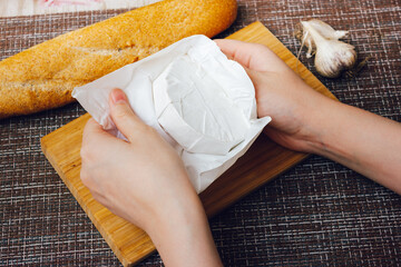 DIY baked cheese camembert instruction step by step. step 1 unpacking camembert.camembert in white paper packaging.cheese with white mold.moldy cheese