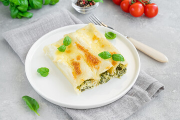 Traditional Italian cannelloni with ricotta and spinach in bechamel sauce with fresh basil leaves...