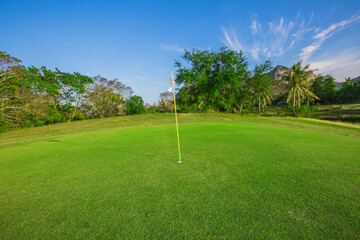 White flag and green grass under blue sky at the beautiful course as goal concept