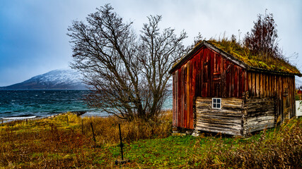 Rote Hütte am Ufer des Fjord an einem stürmischen Tag in Troms, in der Nähe von Tromsö,...