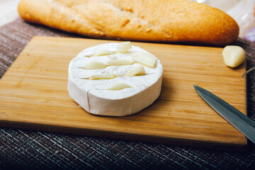 DIY baked cheese camembert instruction step by step. step 2 make cuts on the camembert and insert the garlic into the cuts.cheese with white mold.moldy cheese