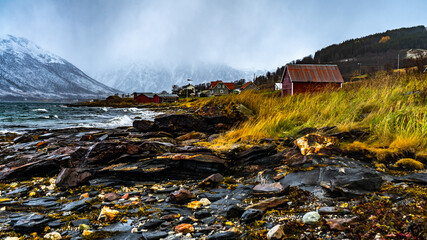 Rote Hütte am Ufer des Fjord an einem stürmischen Tag in Troms, in der Nähe von Tromsö,...