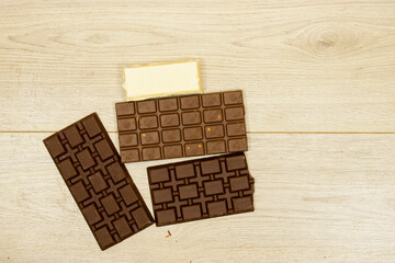 milk and black, white chocolate bars on wood table