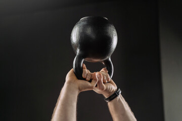 Close up of muscular man's hands holding heavy kettlebell overhead. Hands holding heavy kettle bell...
