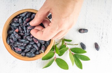 a woman's hand takes a honeysuckle berry from a clay cup lying flat