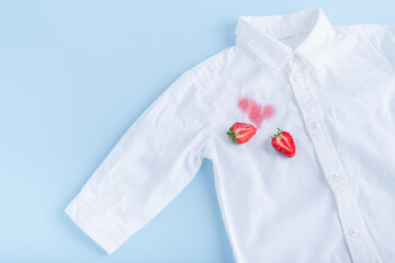 Obraz na płótnie Canvas Dirty stain of strawberry on a white shirt. daily life dirty stain. Isolated on a blue background