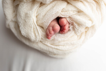 a small leg of the newborn in a white scarf. soft focus