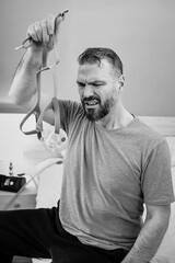 Unhappy shocked man with chronic breathing issues surprised by using  CPAP machine sitting on the bed in bedroom. Healthcare, CPAP, Obstructive sleep apnea therapy, snoring concept