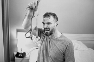 Unhappy shocked man with chronic breathing issues surprised by using  CPAP machine sitting on the...
