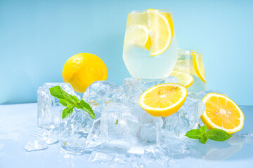 Traditional summer cold refreshing cocktail lemonade, with lemon slices and lots of crushed ice and iced pedestals on blue background
