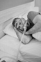 Monochrome portrait of Sleeping man with chronic breathing issues considers using CPAP machine in bed. Healthcare, Obstructive sleep apnea therapy, CPAP, snoring concept