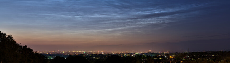 Beautiful panoramic view of very rare noctilucent clouds and stars shining through them seen in...