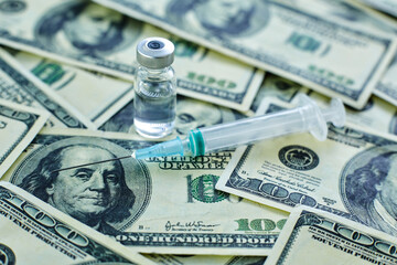 Fototapeta premium Vaccine vial and syringe on the background of one hundred dollar bills
