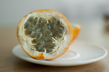 Fresh organic ripe granadilla or yellow passion fruit cut in half on a wooden board. Exotic fruits, healthy eating concept