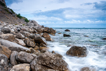 Fototapeta na wymiar Seascape of the Crimean coast. Waves break into beautiful splashes against rocks.