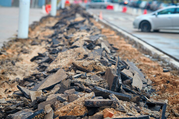 Broken asphalt on pedestrian zone in the city street. Road repair work. Construction of pedestrian zone. Damaged asphalt surface. Road repair.