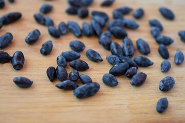 blue honeysuckle berry sprinkled on a beige wooden table